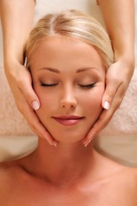 Young woman receiving a head massage in a spa center.